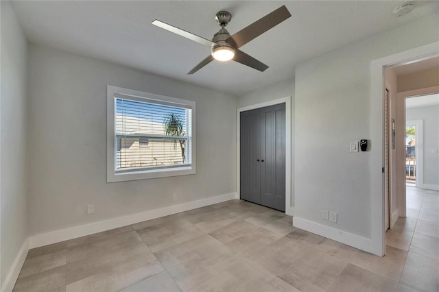 unfurnished bedroom with a ceiling fan, multiple windows, baseboards, and a closet