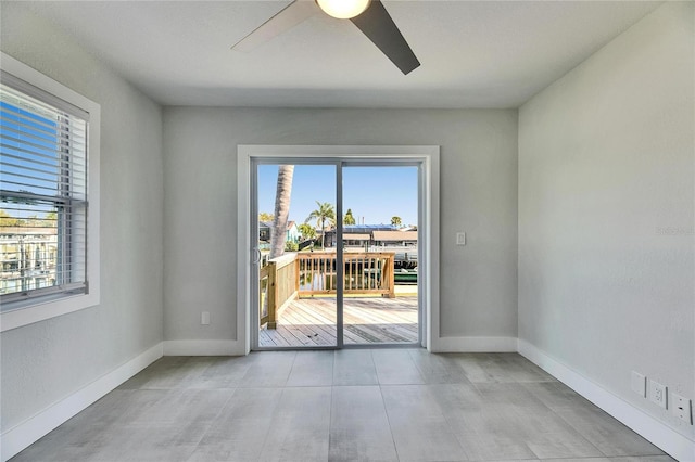 empty room with ceiling fan, plenty of natural light, and baseboards