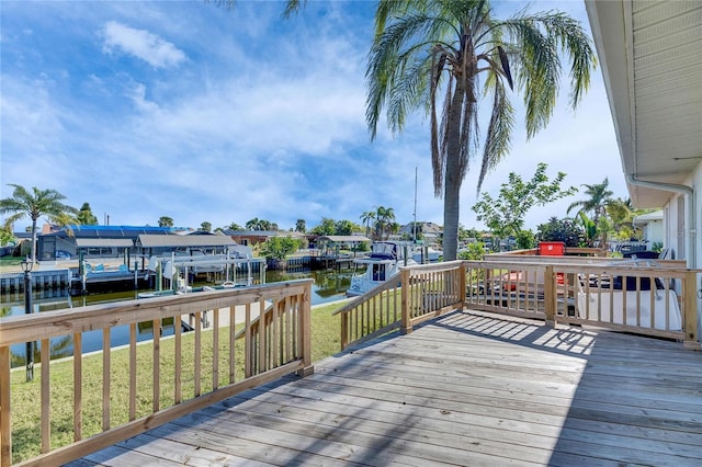 deck featuring a boat dock, a water view, and a lawn