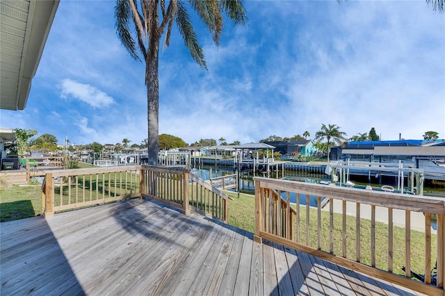 wooden terrace featuring a dock, a water view, a lawn, and boat lift