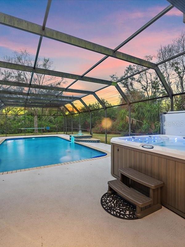 pool featuring a lanai, a patio area, and a hot tub