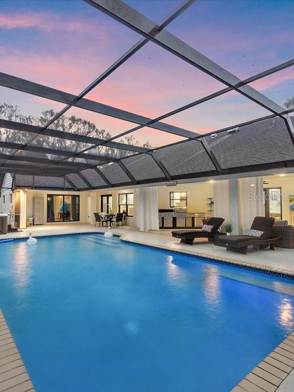 outdoor pool featuring a lanai, central AC unit, and a patio