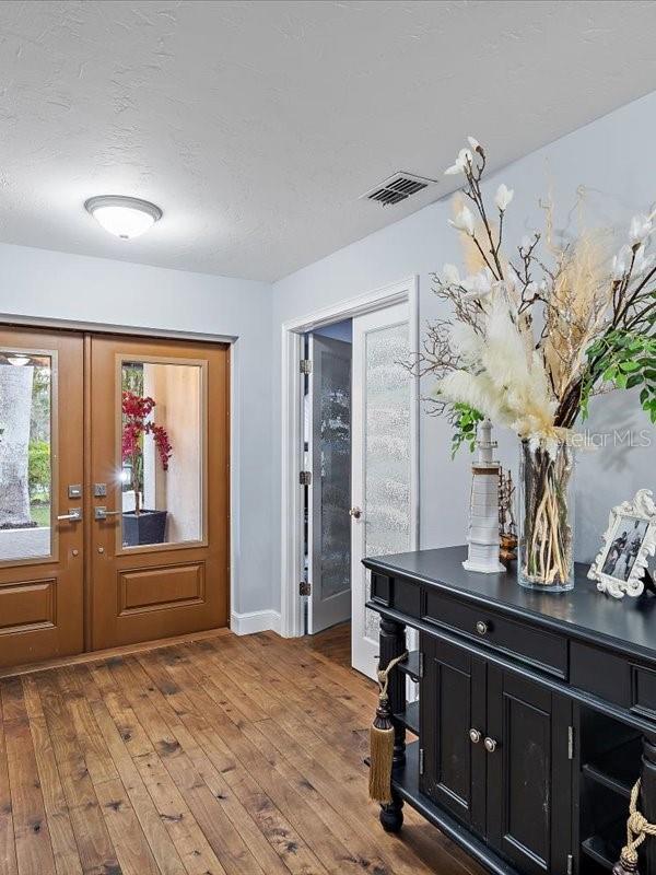 entryway featuring french doors, visible vents, a textured ceiling, and hardwood / wood-style flooring