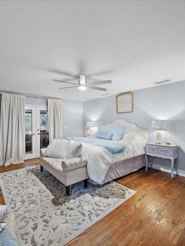 bedroom with visible vents, ceiling fan, wood finished floors, access to outside, and french doors