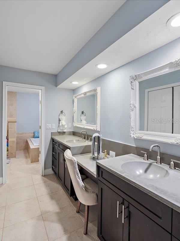 full bathroom with two vanities, tile patterned flooring, a garden tub, and a sink