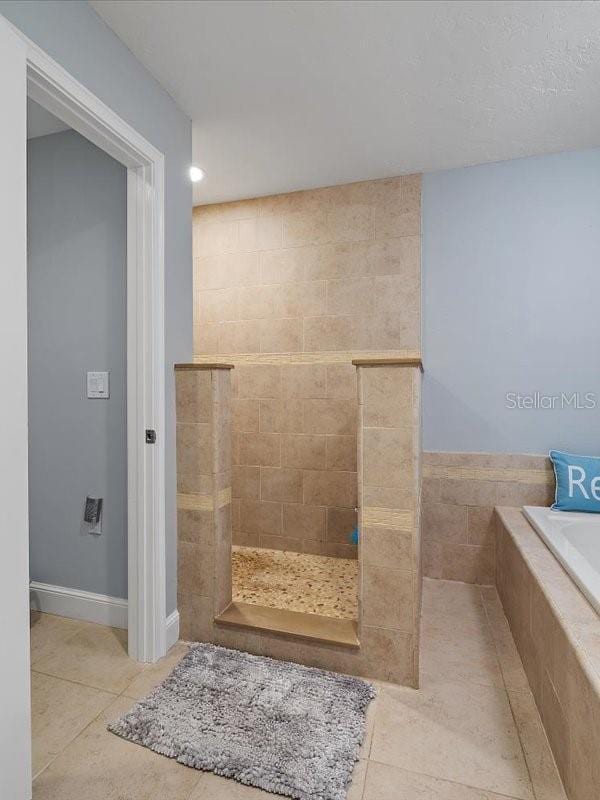 full bath featuring a garden tub, tile patterned flooring, baseboards, and a walk in shower