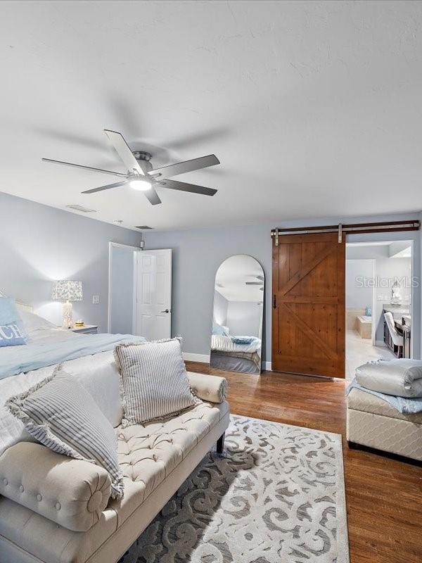 bedroom with arched walkways, ceiling fan, baseboards, and wood finished floors