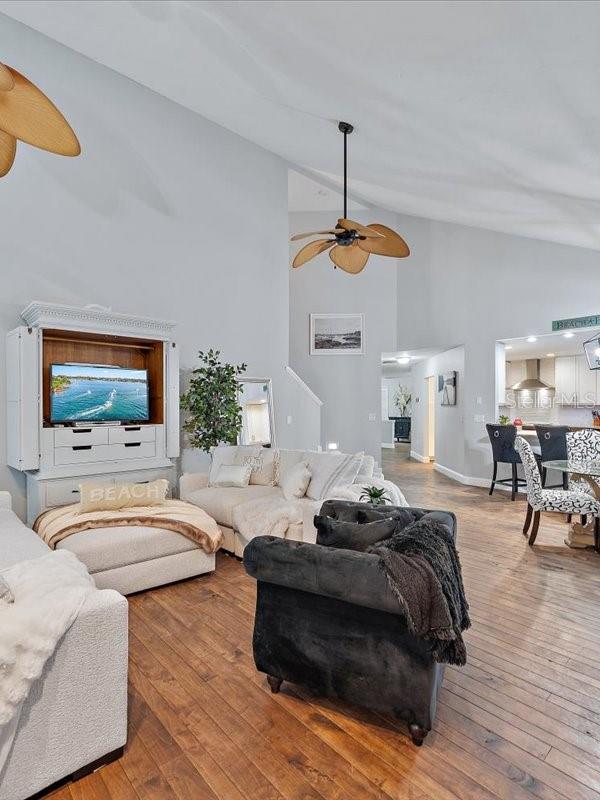 living room with ceiling fan, high vaulted ceiling, and hardwood / wood-style floors