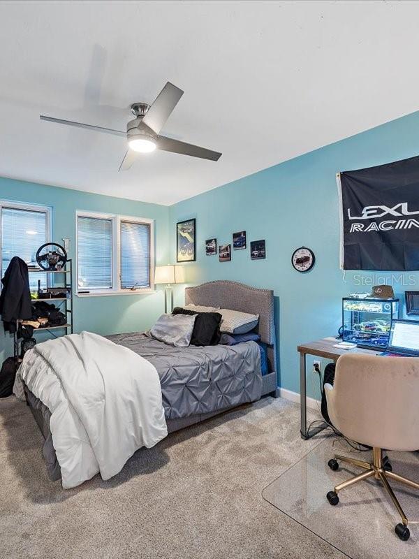 carpeted bedroom with a ceiling fan and baseboards