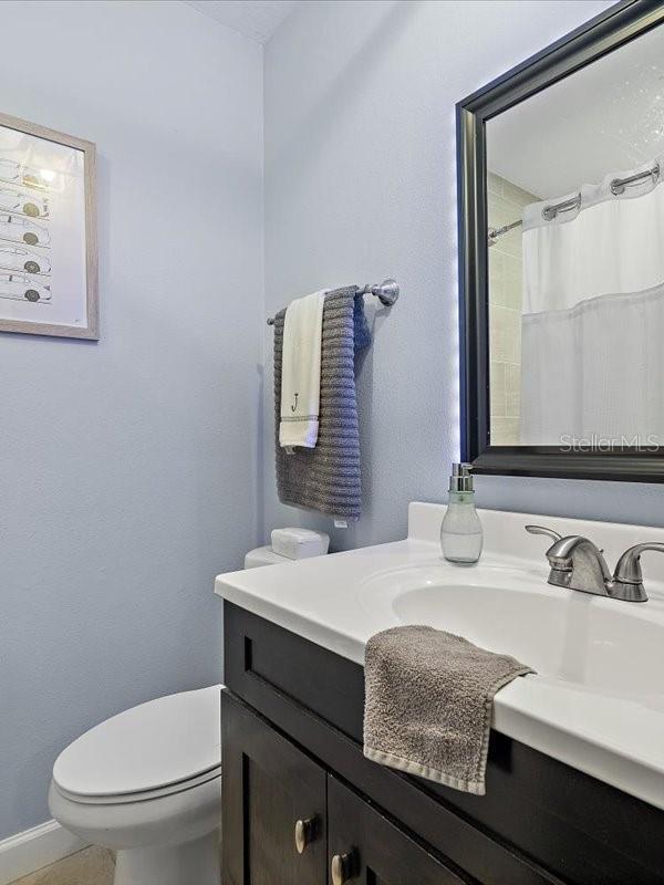 bathroom featuring toilet, curtained shower, and vanity