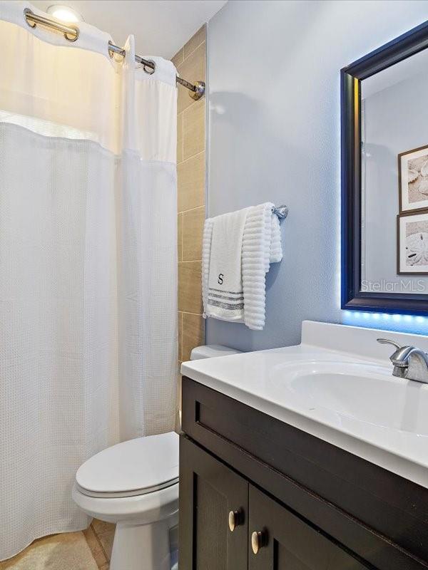 bathroom featuring a shower with curtain, vanity, toilet, and tile patterned floors