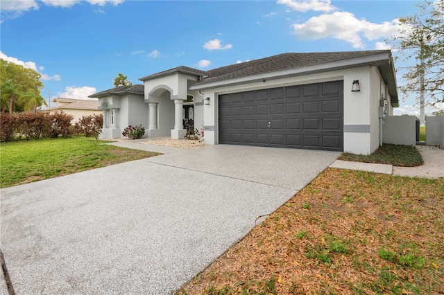 view of front of home featuring an attached garage, concrete driveway, a front yard, and stucco siding