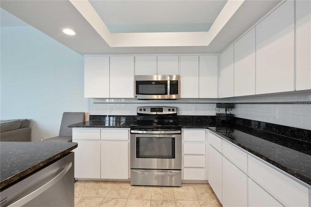 kitchen with white cabinets, dark stone counters, appliances with stainless steel finishes, backsplash, and recessed lighting