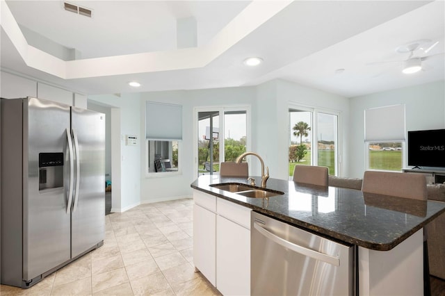 kitchen featuring stainless steel appliances, visible vents, a sink, an island with sink, and dark stone counters