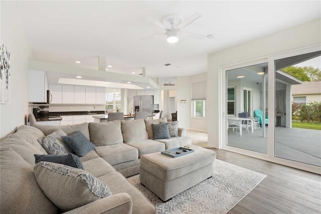 living area with baseboards, recessed lighting, a ceiling fan, and light wood-style floors