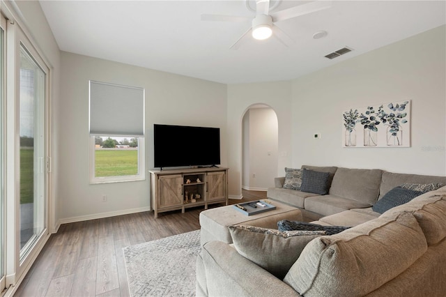 living room featuring baseboards, visible vents, arched walkways, and wood finished floors