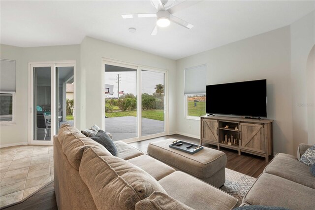 living area featuring a ceiling fan, baseboards, arched walkways, and wood finished floors