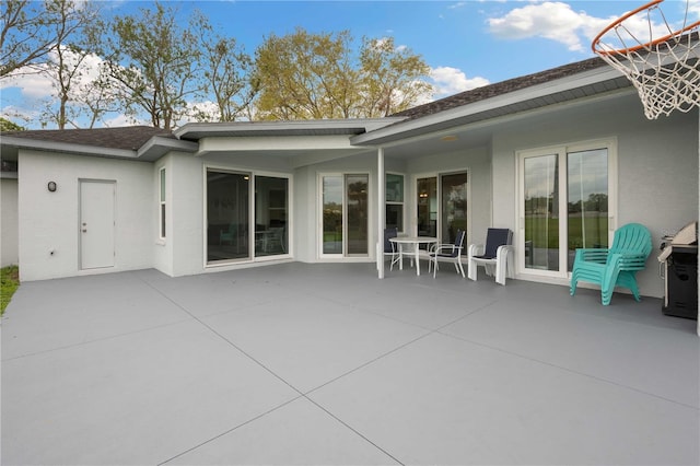 back of house featuring a patio area, roof with shingles, and stucco siding