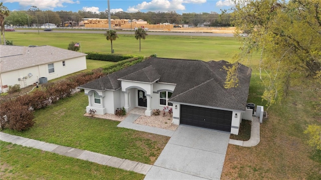 view of front facade with a front lawn, roof with shingles, driveway, and an attached garage