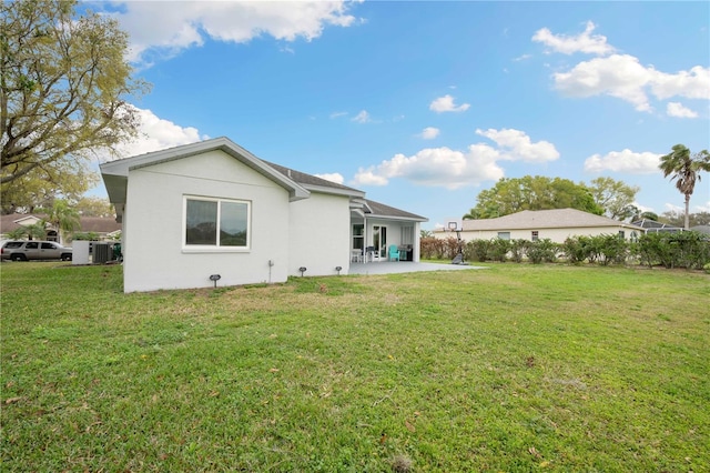 rear view of house with a patio, a yard, central AC unit, and stucco siding