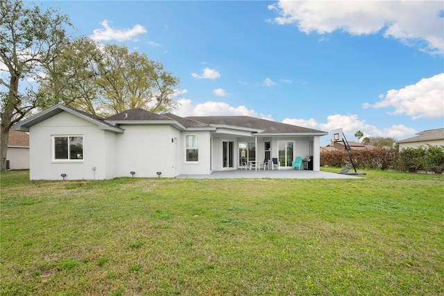 rear view of property with stucco siding, a yard, and a patio