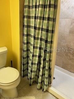 full bathroom with tile patterned flooring, a shower stall, and toilet