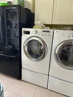 clothes washing area featuring cabinet space, separate washer and dryer, and light tile patterned flooring