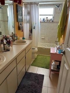 full bath featuring double vanity, toilet, shower / tub combo, a sink, and tile patterned flooring