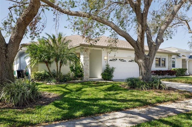 view of front of home with a garage, driveway, a front yard, and stucco siding