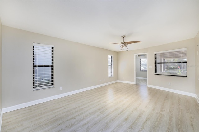 empty room with a ceiling fan, light wood-style flooring, and baseboards