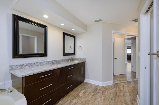 bathroom with baseboards, visible vents, wood finished floors, and vanity