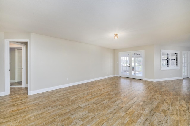 unfurnished room featuring french doors, light wood finished floors, and baseboards