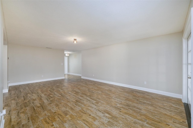 spare room featuring baseboards and wood finished floors