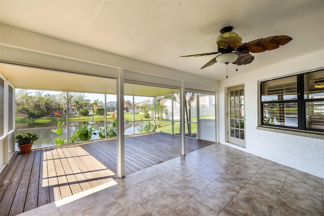 unfurnished sunroom featuring ceiling fan and a water view