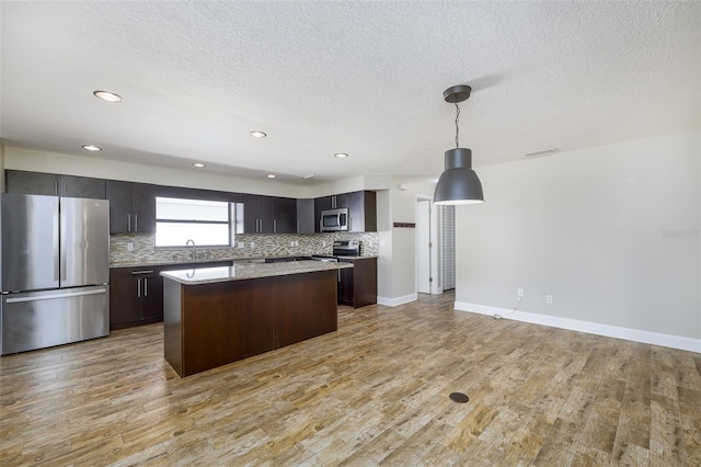 kitchen featuring appliances with stainless steel finishes, light wood-type flooring, a sink, and a kitchen island