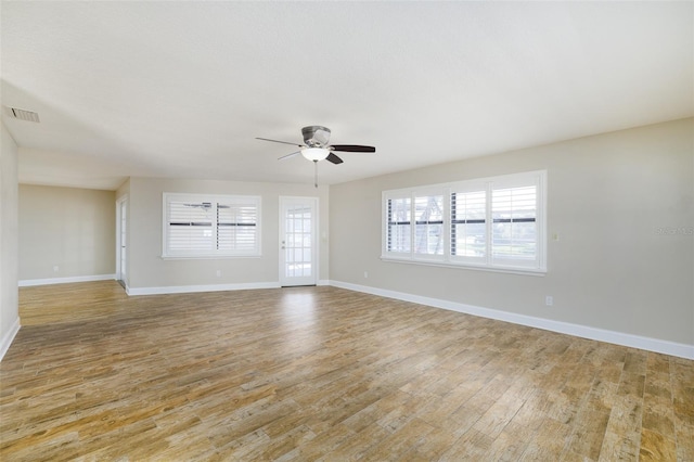 unfurnished room featuring a ceiling fan, visible vents, light wood-style flooring, and baseboards