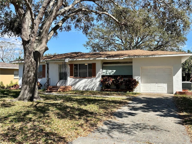 single story home with stucco siding, central AC unit, a front yard, a garage, and driveway