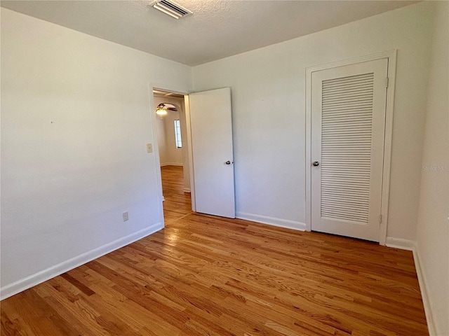 unfurnished bedroom with baseboards, a closet, visible vents, and light wood-style floors