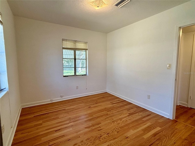 empty room with visible vents, light wood-style flooring, and baseboards