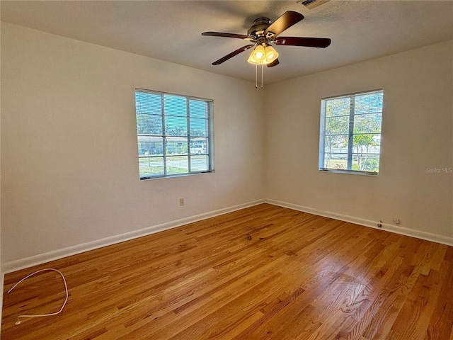 empty room featuring light wood-style floors, ceiling fan, and baseboards