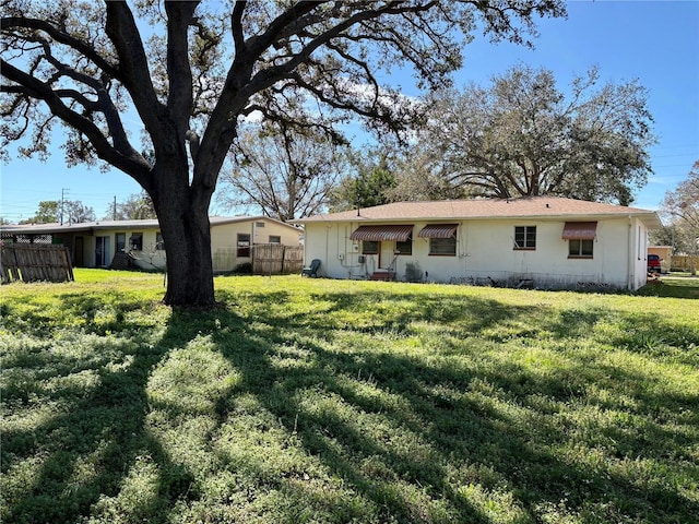 view of front of property with a front yard, fence, and stucco siding