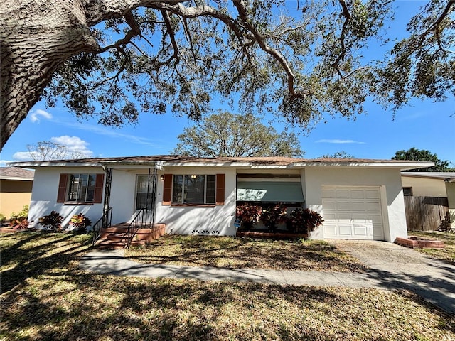 ranch-style home with a garage, driveway, fence, and stucco siding