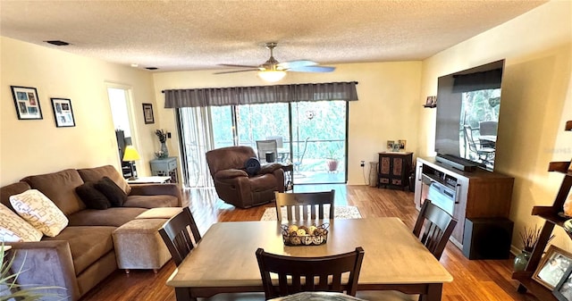 dining space featuring a ceiling fan, a textured ceiling, visible vents, and wood finished floors