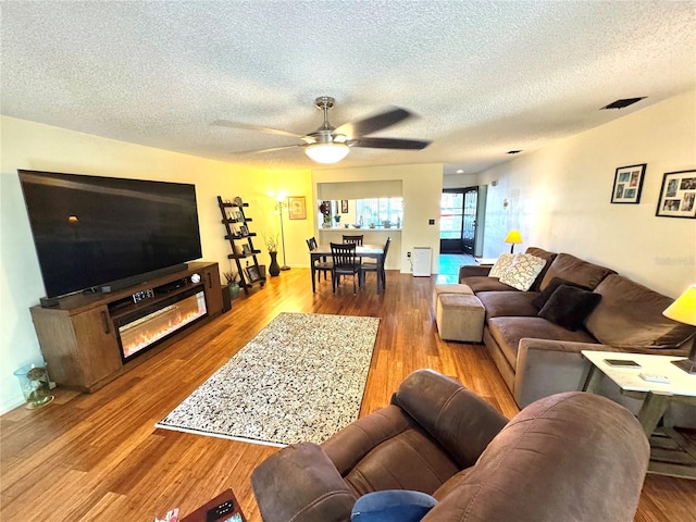 living room featuring a textured ceiling, wood finished floors, and a ceiling fan