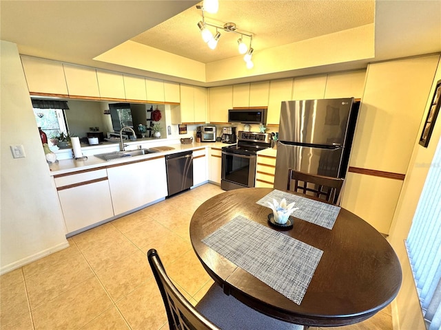 kitchen with a textured ceiling, light tile patterned flooring, stainless steel appliances, a sink, and light countertops