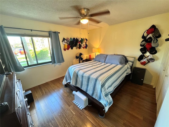 bedroom featuring a ceiling fan, a textured ceiling, baseboards, and dark wood-style flooring