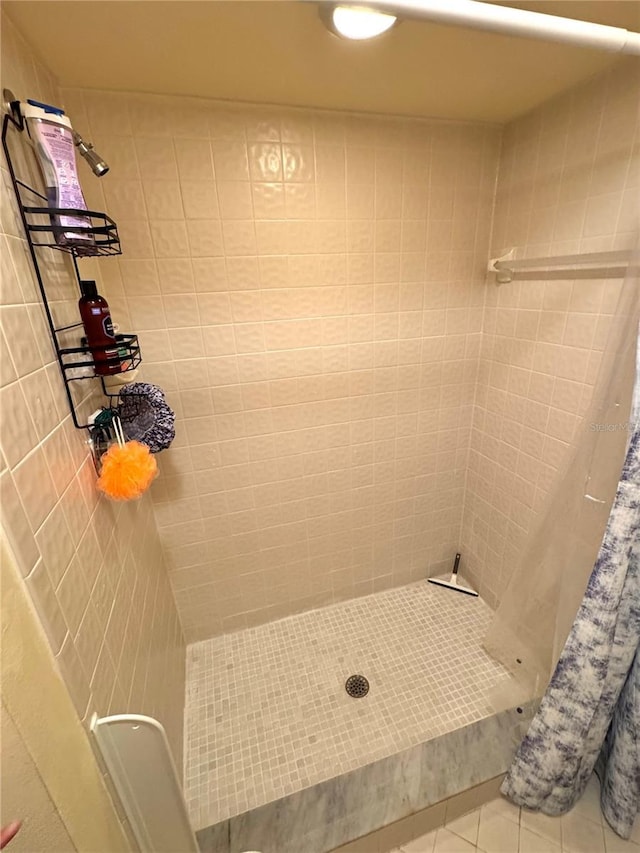 bathroom featuring tile patterned flooring and tiled shower