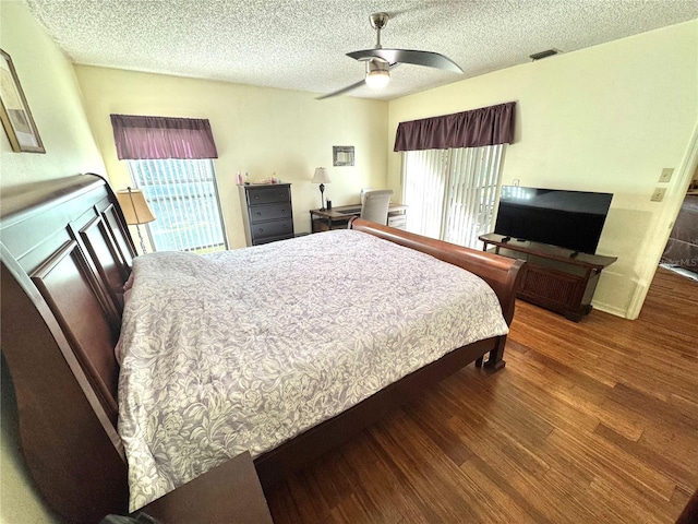 bedroom with ceiling fan, visible vents, dark wood finished floors, and a textured ceiling