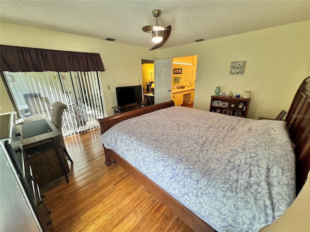 bedroom with access to exterior, a textured ceiling, visible vents, and light wood-style floors