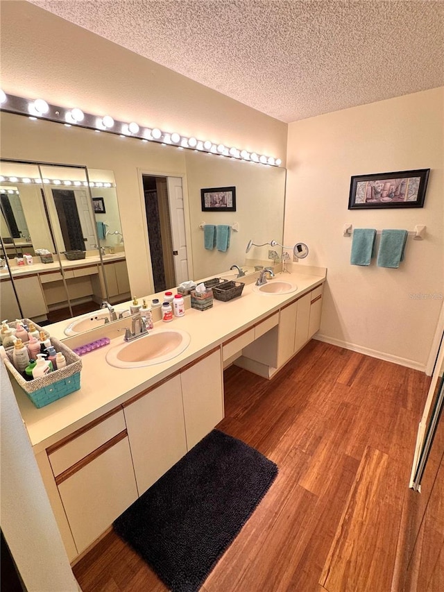 bathroom with a textured ceiling, baseboards, wood finished floors, and vanity